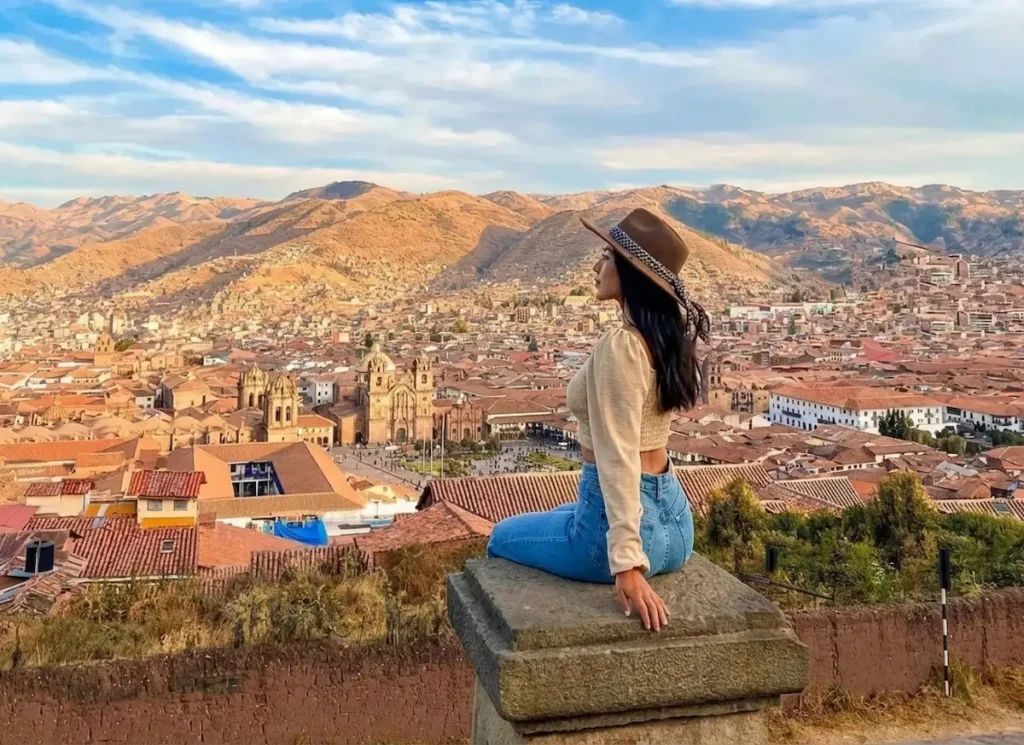Turista desfrutando da vista panorâmica da cidade de Cusco desde o Mirante de São Cristóvão durante o city tour.
