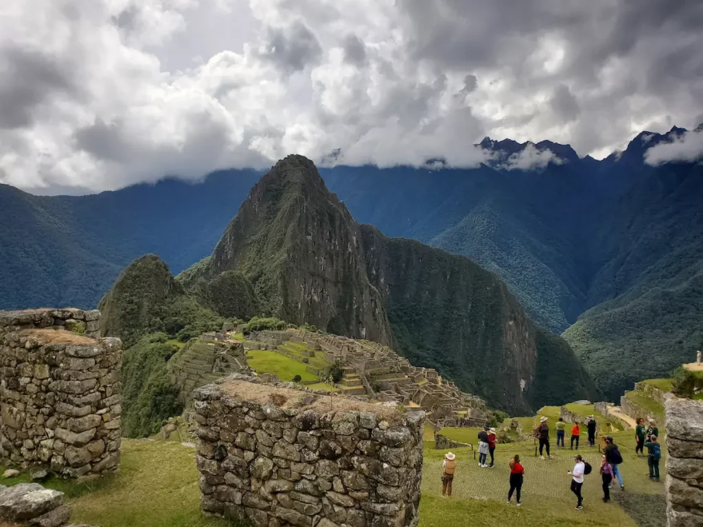Vista panorâmica clássica da cidadela inca de Machu Picchu com as montanhas ao fundo em um dia de sol.